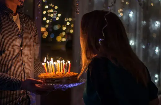 Urodzinowy tort ze świeczkami dla 14 latki, w tle migoczące światełka.