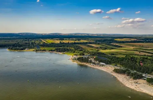 Letnie słońce nad **Jeziorem Chańcza**. Tłumy plażowiczów, zielone lasy i pola tworzą malowniczy krajobraz.