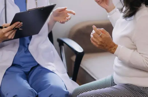 Lekarz w białym fartuchu rozmawia z pacjentką, notując coś na kartce. Czy do psychiatry potrzebne jest skierowanie?