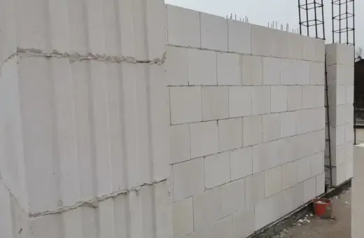 Ściana z bloczków silikatowych wznoszona na budowie. Widać zbrojenie i fragmenty fundamentów.
