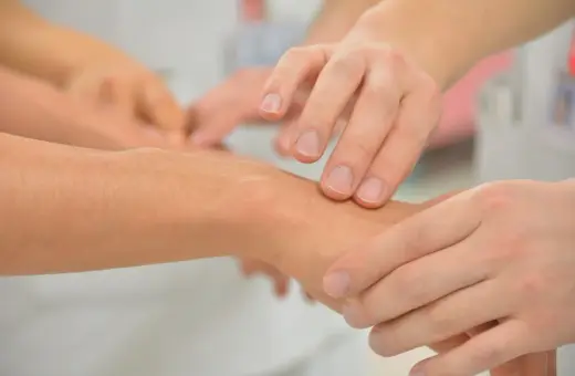 Dłoń lekarza bada nadgarstek pacjenta, szukając oznak drżenia samoistnego nerwicy.