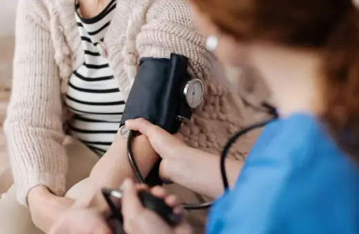 Pielęgniarka mierzy ciśnienie kobiecie w ciąży. Monitorowanie podwyższonego ciśnienia pod koniec ciąży jest kluczowe dla zdrowia mamy i dziecka.