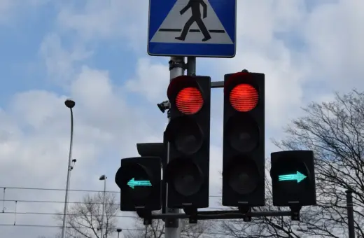 Sygnalizacja świetlna: czerwone światła dla jazdy prosto, zielona strzałka w lewo. Czy na strzałce w lewo można zawracać? Znak przejścia dla pieszych.