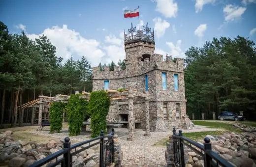 Kamienny zamek z polską flagą, otoczony lasem. Czy to właśnie tutaj jest Podlasie?