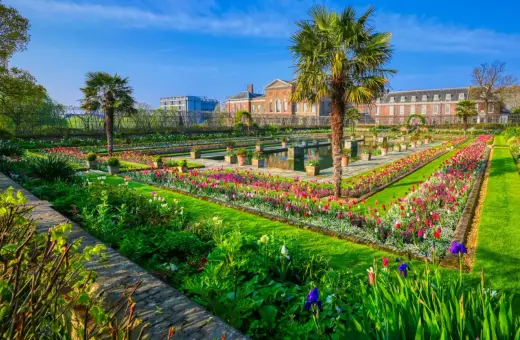 Kwiatowe rabaty i palmy w ogrodach Kensington Palace, Londyn.