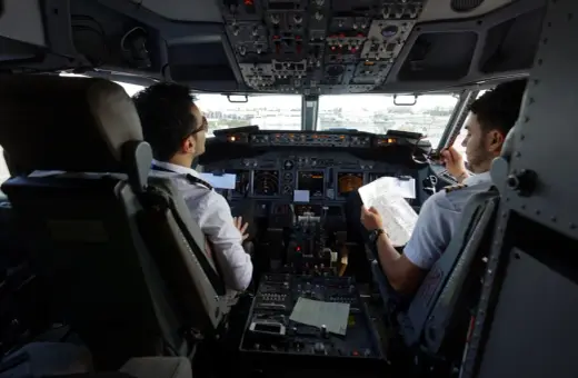 Dwóch pilotów w kokpicie samolotu, dyskutujących o trasie. Ciekawe, ile zarabia pilot Ryanair?
