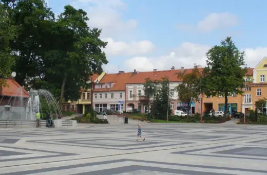 Dziecko biega po placu z fontanną, otoczonym kamienicami. To największy rynek w Polsce, tętniący życiem.