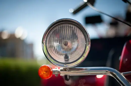 Chromowany reflektor i pomarańczowy kierunkowskaz motoroweru. Czy motorower musi mieć kierunkowskazy? Tak, dla bezpieczeństwa.