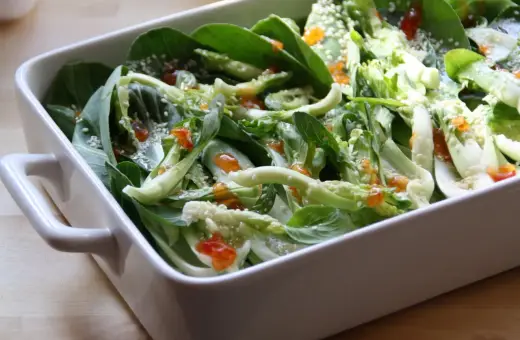 Pyszna kapusta pak choi po tajsku, polana sosem i posypana sezamem, w białej ceramicznej misie.