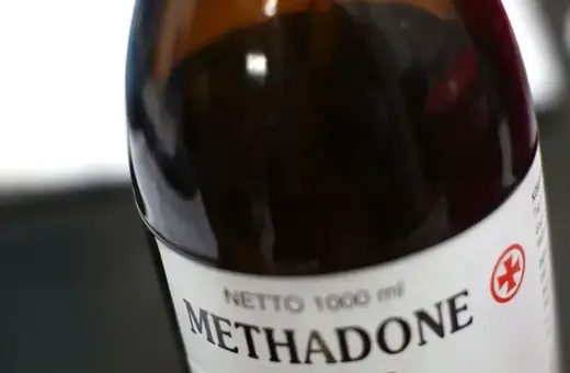 Butelka z ciemnobrązowego szkła z etykietą "Methadone" i symbolem krzyża.