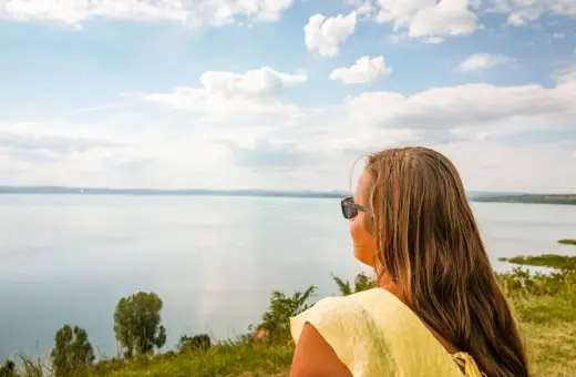 Kobieta w okularach przeciwsłonecznych podziwia rozległe jezioro Balaton.