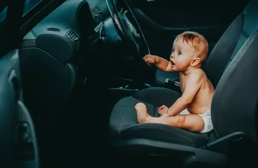 Maluch siedzi za kierownicą, jakby zastanawiał się, od kiedy dziecko może jeździć z przodu.