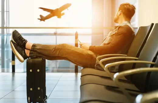 Mężczyzna czeka na lotnisku, nogi na walizce, samolot Wizzair startuje. Czyżby overbooking?
