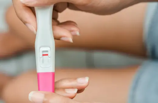 Dłoń trzyma test ciążowy z jedną czerwoną kreską. Kiedy zrobić test ciążowy? Najlepiej po terminie spodziewanej miesiączki.