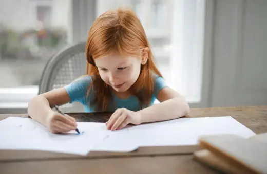 Ruda dziewczynka rysuje. Jej skupienie i zaangażowanie to cechy, które doceni każdy pedagog specjalny, posiadający odpowiednie kwalifikacje.