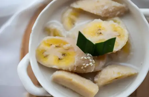 Kawałki banana w mleku kokosowym, ozdobione liściem pandanu i sezamem. Pyszny tajski deser.