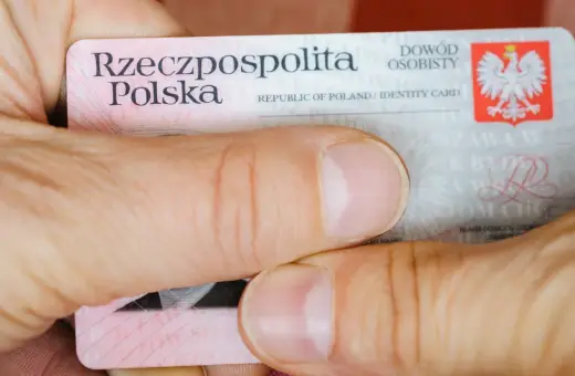 Dłonie trzymają polski dowód osobisty. Widoczny jest numer dowodu osobistego.