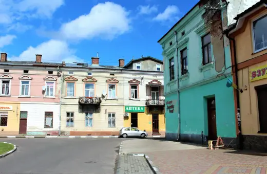 Kolorowe kamienice przy ulicy, gdzie mój stryj kiedyś mieszkał. Srebrny samochód zaparkowany obok apteki.
