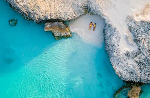 Para na plaży na wyspie Aruba, otoczeni turkusową wodą i skalistymi klifami. Idealne miejsce na relaks.