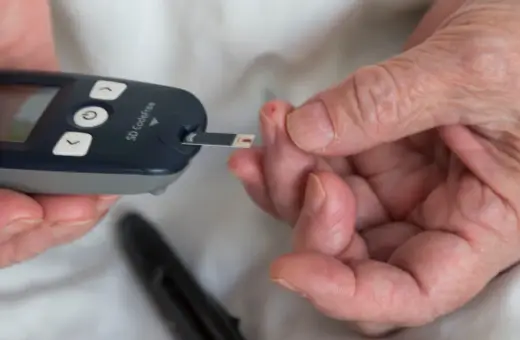 Osoba z **stanem przedcukrzycowym** mierzy poziom glukozy we krwi glukometrem.