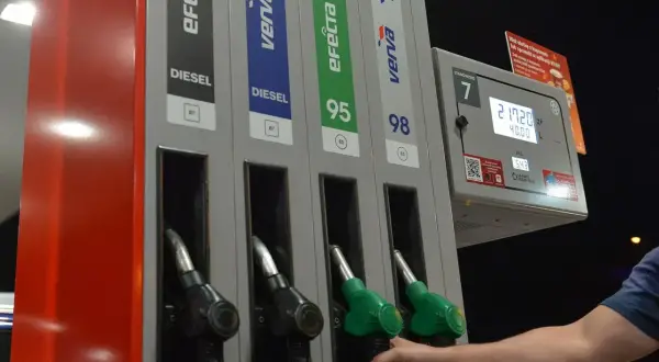 Dłoń sięga po dystrybutor z napisem DIESEL. Na stacji paliw można wybrać różne rodzaje paliwa, w tym diesel.