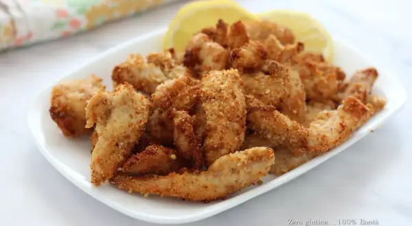 Straccetti di pollo croccanti e dorati, cotti in friggitrice ad aria, serviti con spicchi di limone.
