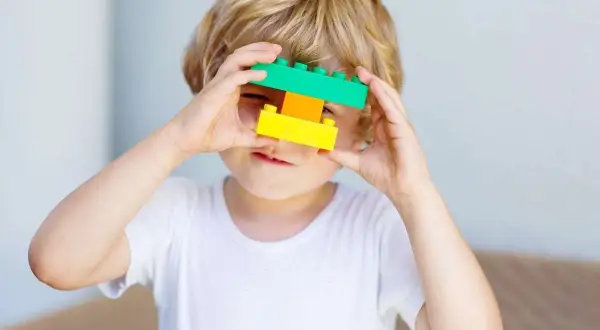 5 letnie dziecko bawi się klockami, tworząc z nich okulary.