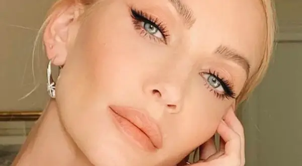 Primo piano di una donna con un elegante trucco occhi, labbra nude e orecchini a cerchio.