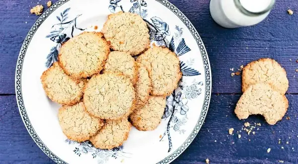 En tallrik med hembakade havrekakor, perfekt för ett enkelt havrekakor recept. En flaska mjölk står bredvid.