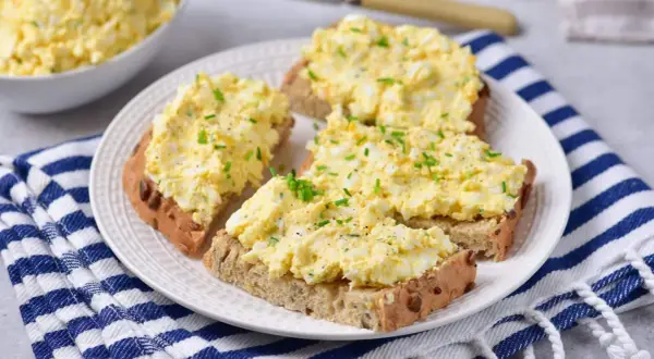 Pyszna pasta jajeczna z twarogiem na chlebie, posypana szczypiorkiem. Idealna na śniadanie lub przekąskę.