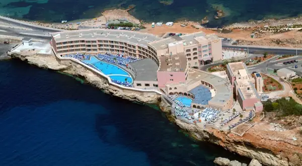 Widok z lotu ptaka na Paradise Bay Resort z basenami i leżakami, położony na klifie nad turkusowym morzem.