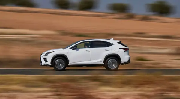 Biały suv Lexus NX 350h jedzie po pustynnej drodze, rozmywając krajobraz.