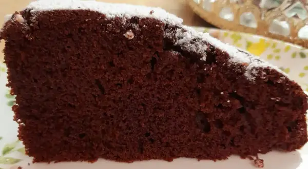 Una fetta di torta al cioccolato soffice, spolverata di zucchero a velo. Un'idea golosa per una torta mascarpone e cioccolato.