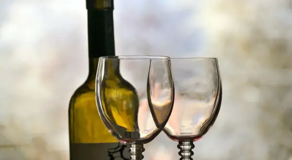 Butelka białego wina i dwa puste kieliszki, gotowe na orzeźwiające wino z tonikiem.