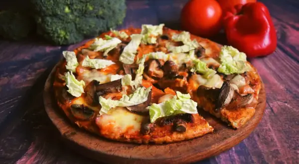 Pyszna pizza z twarogu z pieczarkami i kapustą pekińską, obok brokuły i pomidory.