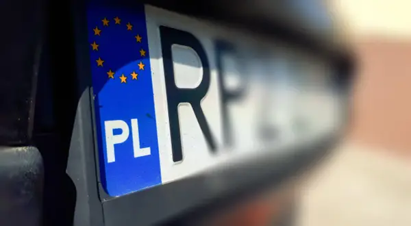Zbliżenie na polską tablicę rejestracyjną z symbolem Unii Europejskiej. Litery "PL" i fragment numeru rejestracyjnego.
