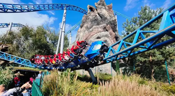 Kolejka Blue Fire w Europa Park Niemcy pędzi po niebieskich torach obok skalistej góry.