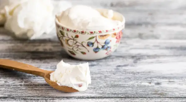 Cremiger Quark auf einem Holzlöffel und in einer Schale. Ja, ist Quark gesund und lecker!