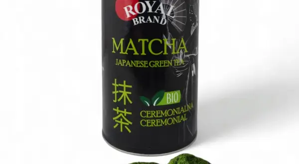Czarna puszka z zieloną herbatą matcha Royal Brand i garść proszku matcha na białym tle.