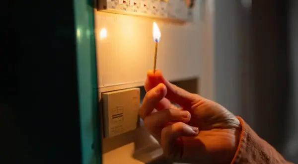 Mano con fiammifero acceso vicino al quadro elettrico, per capire cosa fare se salta la corrente.