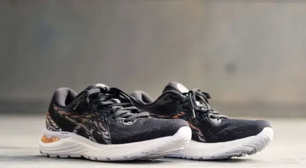 Scarpe da corsa Asics Gel Cumulus 23 nere con dettagli in bronzo e suola bianca, pronte per ogni avventura.
