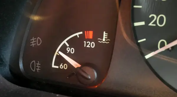 Le témoin de température moteur s'allume, indiquant une **cause surchauffe moteur essence**. Le thermomètre est proche de 120°C.