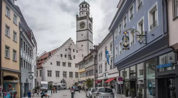 Der Blaserturm Ravensburg ragt über eine belebte Gasse mit Geschäften und Menschen.