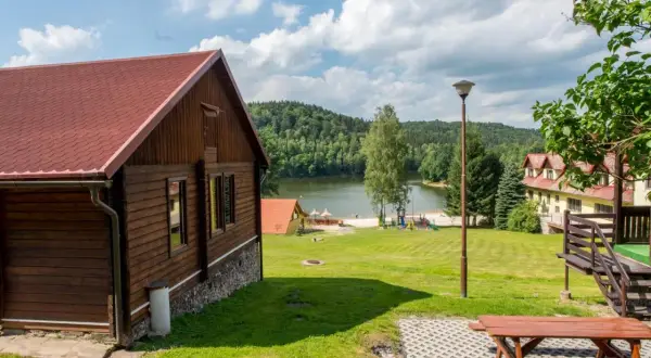 Drewniane domki nad jeziorem w Dolnośląskim. Piękny krajobraz z zielonymi wzgórzami i jeziorem.