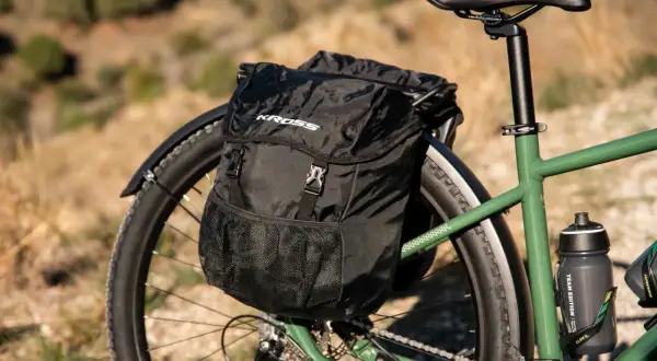 Czarna torba rowerowa Kross na bagażniku, gotowa na przygodę na trasie rowerowej R1. W tle suchy krajobraz.