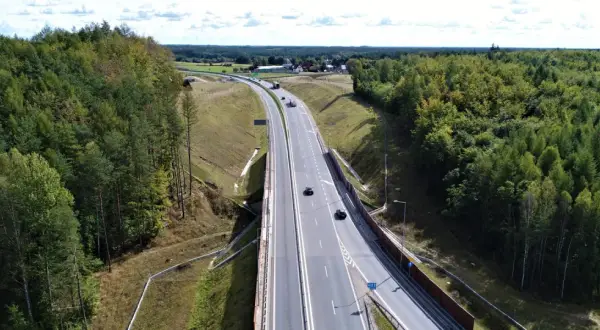 Droga krajowa 22 przecina gęsty las. Samochody poruszają się po wielopasmowej jezdni, otoczonej zielenią.