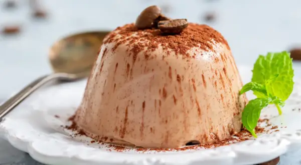 En krämig italiensk pannacotta, pudrad med kakao och toppad med kaffebönor. En frisk myntakvist ger en fin kontrast.