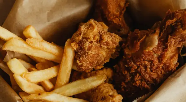 Krispiga chicken nuggets och gyllene pommes frites i en brun papperspåse. En klassisk kombination för en snabb och god måltid.