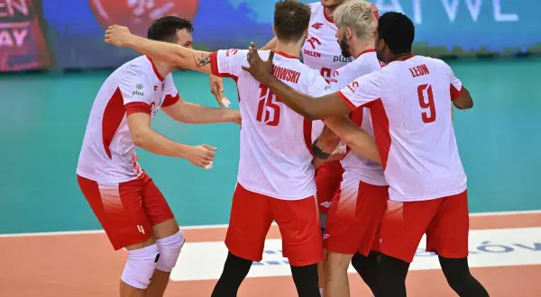 Siatkarze reprezentacji Polski w biało-czerwonych strojach świętują na boisku.