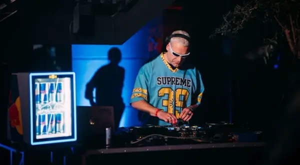 DJ Inox w niebieskiej koszulce z numerem 39 gra muzykę na konsoli DJ-skiej.